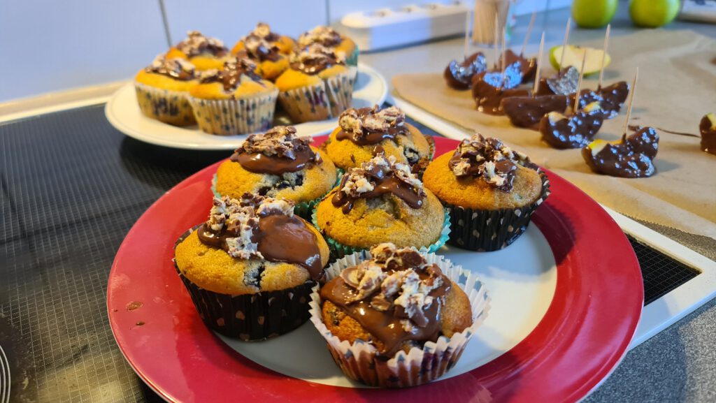 Muffins mit Schoko-Bons und Schokoladenguss auf einem roten Teller