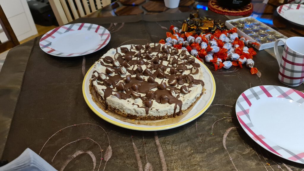 Schoko-Bons-Torte mit Schokoladenstreifen auf dem gedeckten Tisch, daneben Schoko-Bons
